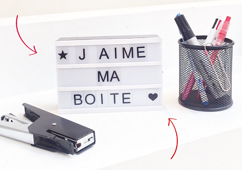 Lightbox avec écrit "j'aime ma boite" entourée d'une agrafeuse et d'un pot à crayons