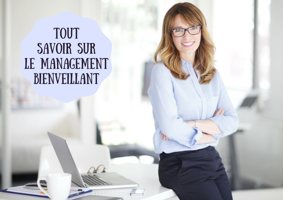 Femme manager bras croisés souriant adossée à un bureau 