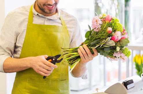 Fleuriste en train de couper les tiges d'un bouquet