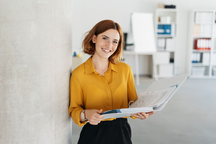 Souriante jeune employé de bureau tenant un gros fichier